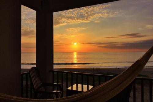 a hammock on the balcony of a resort with a sunset at Punta Zicatela Hotel - Adults Only in Puerto Escondido