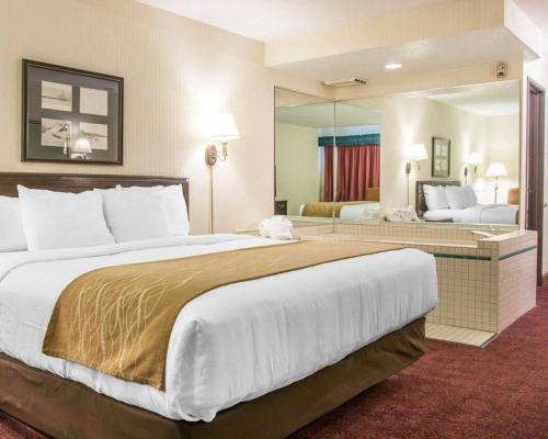 a large bed in a hotel room with a large mirror at Comfort Inn Lakeside in Mackinaw City