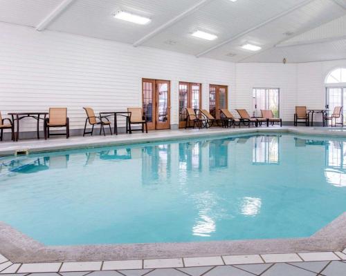 ein großer Pool mit Stühlen und Tischen in einem Gebäude in der Unterkunft Comfort Inn Lakeside in Mackinaw City