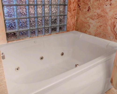 een badkamer met een wit bad en een raam bij Comfort Inn of Livonia in Livonia