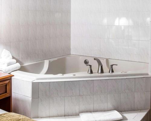 a white bath tub with two faucets in a bathroom at Quality Inn in Southfield