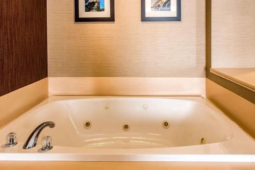 a white bath tub in a bathroom with two pictures at Comfort Inn in Chelsea