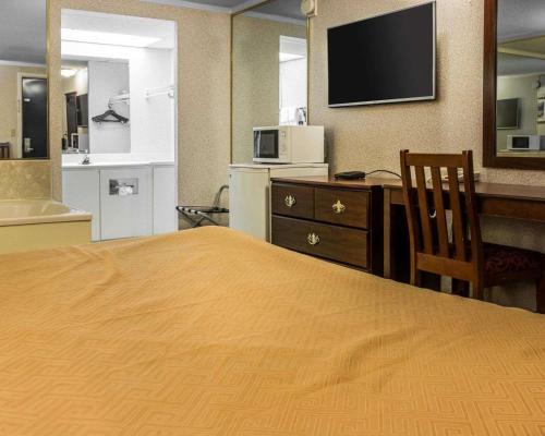 a hotel room with a bed and a desk and a television at Rodeway Inn Madison Heights - Detroit in Madison Heights