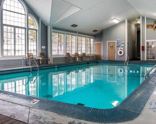 a swimming pool with blue water in a building at Clarion Hotel Beachfront in Mackinaw City
