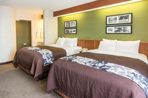 two beds in a hotel room with green walls at Sleep Inn & Suites Bay View Acme - Traverse City in Traverse City