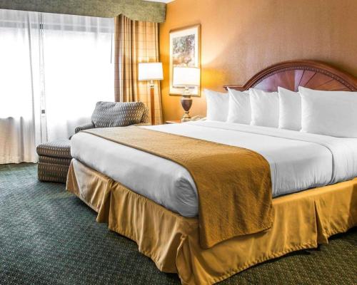 a hotel room with a large bed and a chair at Quality Inn in Southfield