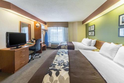 a hotel room with two beds and a desk with a television at Sleep Inn & Suites Bay View Acme - Traverse City in Traverse City