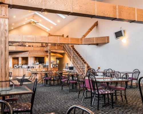 a dining room with tables and chairs and a staircase at Clarion Hotel Beachfront in Mackinaw City