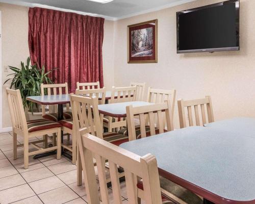 Rodeway Inn Madison Heights - Detroit في ماديسون هايتس: غرفة طعام بها طاولات وكراسي وتلفزيون بشاشة مسطحة