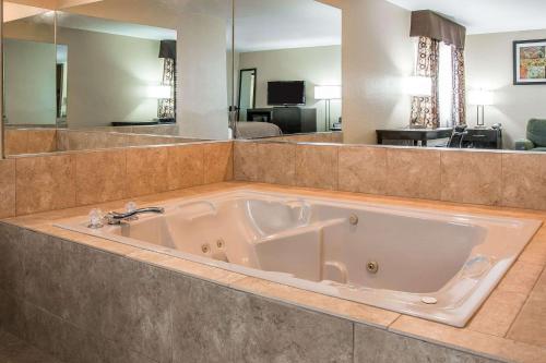 y baño con bañera grande y espejo grande. en Quality Inn Grand Rapids South-Byron Center, en Grand Rapids