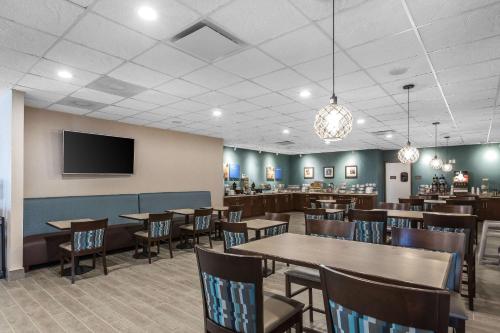 a dining room with tables and chairs and a tv at Comfort Inn Bay City - Riverfront in Bay City