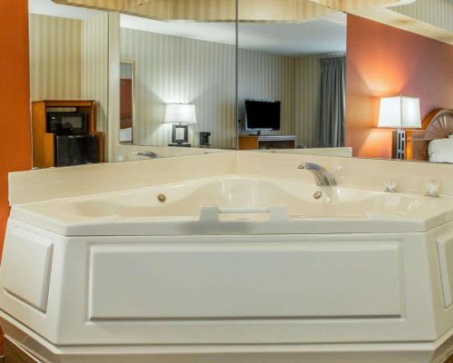 een groot wit bad met een grote spiegel bij Quality Inn in Gaylord