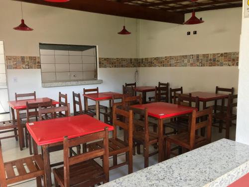 a classroom with red tables and wooden chairs at Pousada Tio Loco in Serra do Cipo