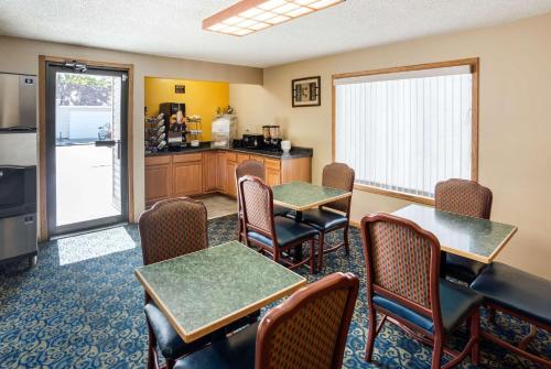 a dining room with tables and chairs and a kitchen at Rodeway Inn & Suites Austin I-90 in Austin
