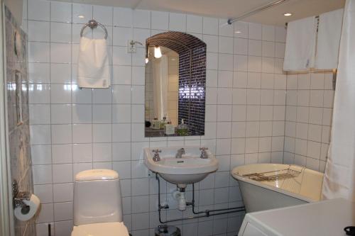 a white tiled bathroom with a toilet and a sink at Executive Living Old Town Unique in Stockholm
