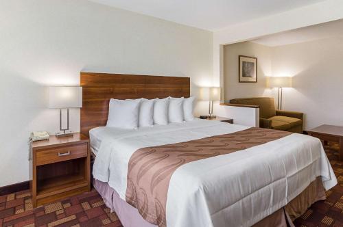 a hotel room with a large bed and a chair at Econo Lodge Luverne I-90 in Luverne