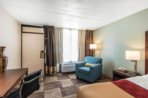 a hotel room with a bed and a blue chair at Econo Lodge Oak Grove-Blue Springs in Oak Grove