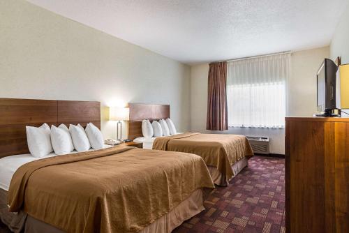 a hotel room with two beds and a flat screen tv at Econo Lodge Luverne I-90 in Luverne