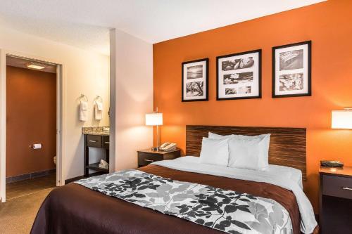 a bed in a hotel room with orange walls at Sleep Inn Springfield South I60 near Medical District in Springfield