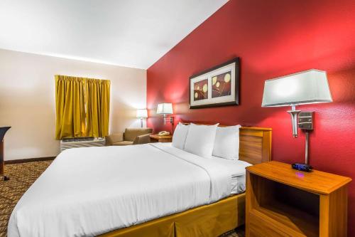 a hotel room with a bed and a red wall at Quality Inn & Suites Chesterfield Village in Springfield