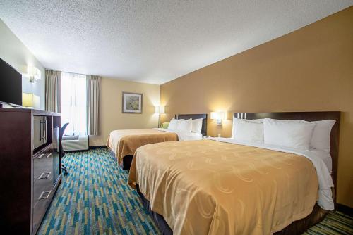 a hotel room with two beds and a television at Quality Inn Near Six Flags St. Louis in Pacific