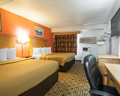 a hotel room with two beds and a chair at Econo Lodge Kansas City Downtown North in Kansas City