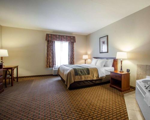 a hotel room with a bed and a desk and a window at Comfort Inn & Suites Harrisonville in Harrisonville