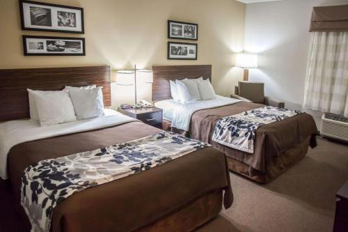 Habitación de hotel con 2 camas y 2 lámparas en Sleep Inn & Suites Indoor Waterpark, en Liberty