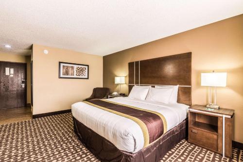 a hotel room with a large bed and a chair at Quality Inn in West Plains