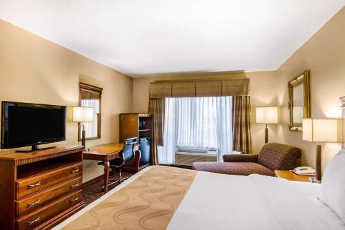 a hotel room with a bed and a flat screen tv at Quality Inn & Suites in Carthage