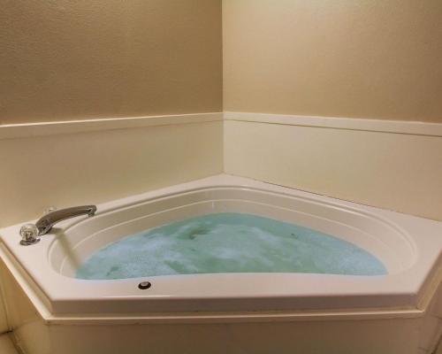 a bath tub filled with blue water with a faucet at Quality Inn & Suites in Hattiesburg