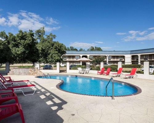 a swimming pool with red chairs and a building at Econo Lodge Grenada in Grenada