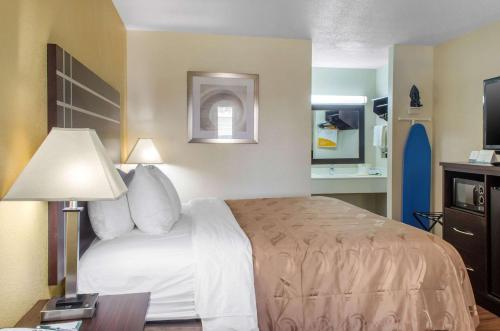 a hotel room with a bed and a table with a lamp at Quality Inn McComb in McComb