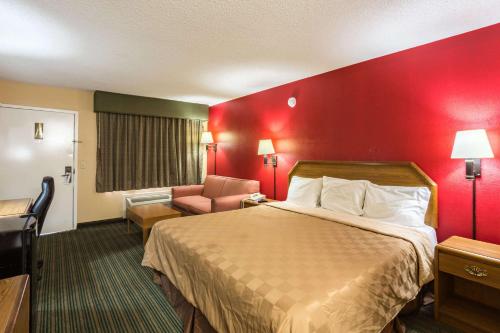 a hotel room with a bed and a red wall at Rodeway Inn in Hazlehurst