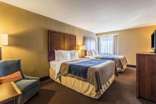 una habitación de hotel con 2 camas y una silla en Comfort Inn, en Tupelo