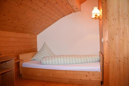 un letto in una cabina di legno con un cuscino sopra di Bauernhof Schneider a Egg