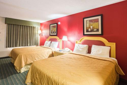 two beds in a hotel room with red walls at Rodeway Inn in Hazlehurst