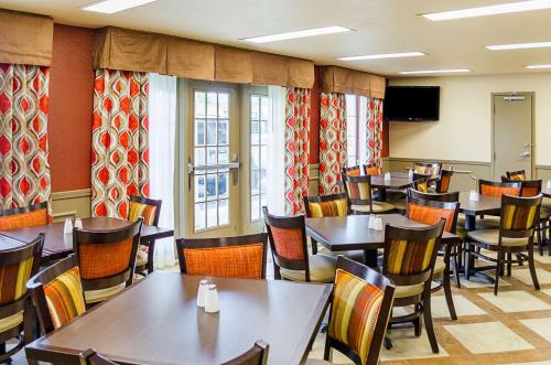 Quality Inn Vicksburg في فيكسبيرغ: مطعم مع طاولات وكراسي وتلفزيون بشاشة مسطحة