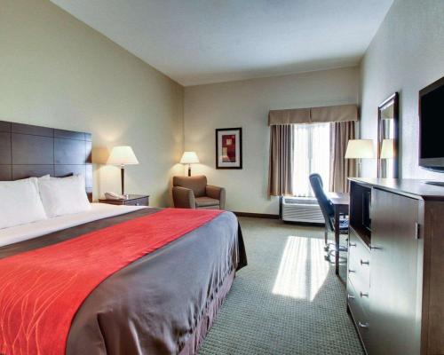 a hotel room with a large bed and a desk at Comfort Inn Moss Point Pascagoula in Moss Point
