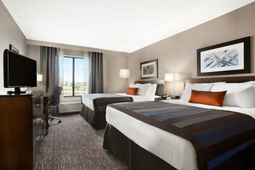 a hotel room with two beds and a flat screen tv at Wingate by Wyndham Corpus Christi in Corpus Christi