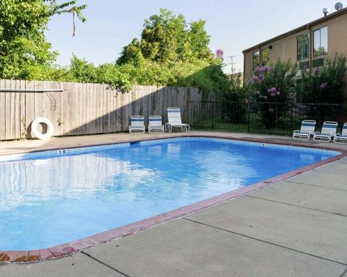 a swimming pool in a yard with chairs and a fence at Econo Lodge in Yazoo City