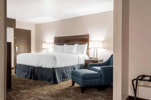 a bedroom with a large bed and a blue chair at Copper King Convention Center, Ascend Hotel Collection in Butte