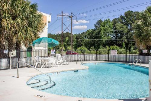 a swimming pool with chairs and an umbrella at Quality Inn in Selma