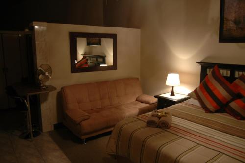 a bedroom with a bed and a couch and a mirror at Bon A Vie Self-catering and b&b Gonubie Full Solar Power, no load shedding! in Gonubie