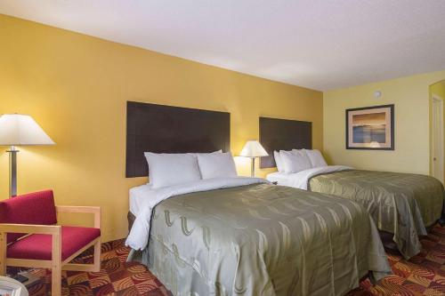 una habitación de hotel con 2 camas y una silla roja en Quality Inn, en Washington
