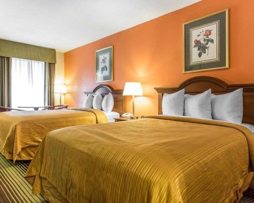 2 camas en una habitación de hotel con paredes de color naranja en Townhouse Winston Salem - University, en Winston-Salem
