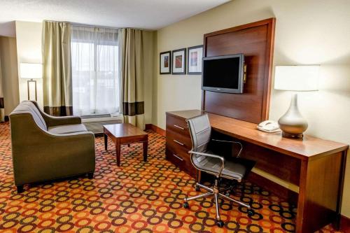 a hotel room with a desk and a television at Concord Suites by IHG in Concord