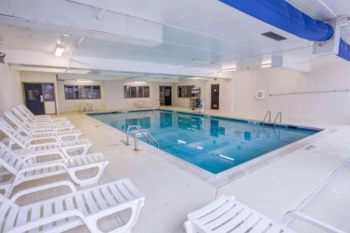 a large swimming pool with white chairs around it at Comfort Suites Concord Mills in Concord