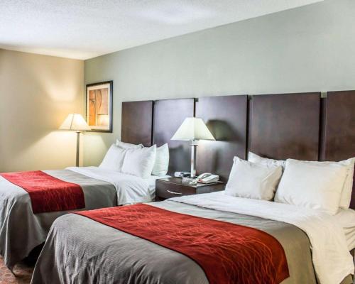 Habitación de hotel con 2 camas con sábanas rojas en Quality Inn Raleigh Downtown, en Raleigh