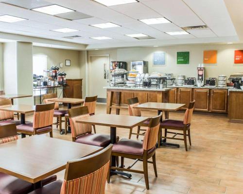 a dining room with tables and chairs and a kitchen at Comfort Inn Fayetteville near Fort Bragg in Fayetteville